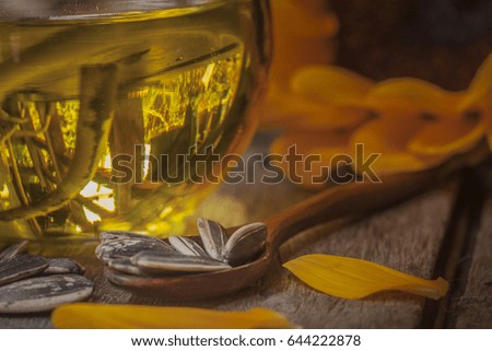 Sunflower oil in bottle glass and Glass Jar with seed on wooden table.