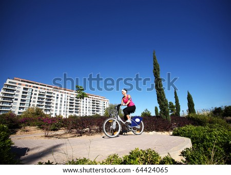 A picture of a young woman cycling in the park during sunny day