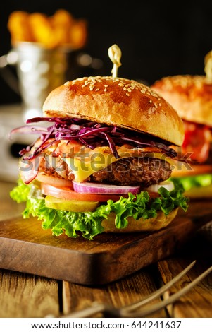 Closeup of delicious fresh homemade hamburger on wooden  dark background.