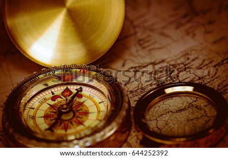 Old golden compass with magnifier and map