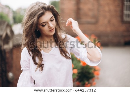 Portrait of a beautiful girl dressed in white and standing near the flowers