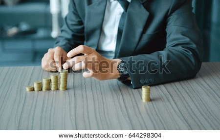 Businessman Stacking Coins in Increasing Order at desk
