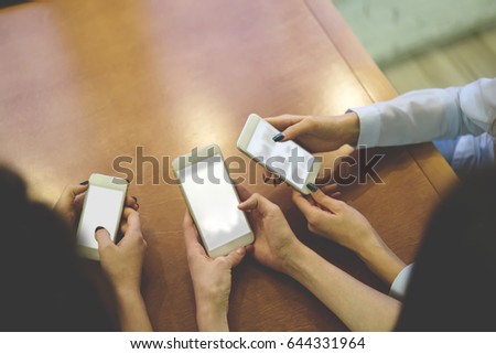 Top view cropped image of hands surfing in internet and typing text messages on blank screen of modern cellphones,chatting online on digital smartphones with mock up for your advertise content