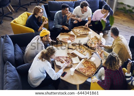 Group of male and female coworkers having  lunch break eating pizza together in office, overhead shot of young casually dressed staff members recreating after finishing tasks making fast snack 
 Royalty-Free Stock Photo #644341861