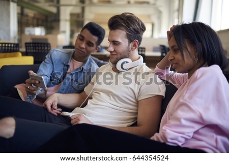Cheerful teenagers reading funny comments under photos published in social networks via cellphone connecting to 4G internet,smiling best friends watching video on mobile phone enjoying free time 
