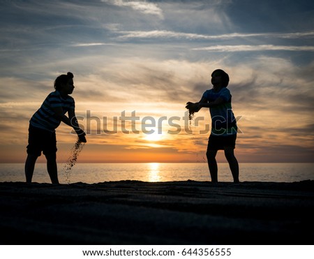 Two happy brothers enjoying beach together at sunset