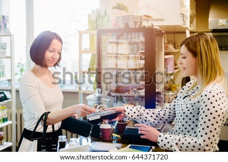 Woman paying with credit card in a cafe or bakery