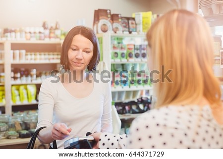 Woman paying with contactless credit card in shop