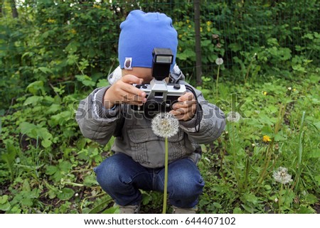 A little boy is taking pictures of a white dandelion. Babe irers in the photographer in role-playing games of great importance in the development of children. A young photographer takes a flower.