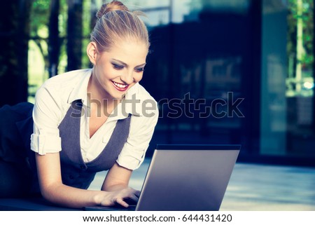Young attractive business woman using laptop in an urban setting. Business concept. Toned image