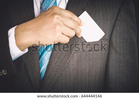 Young businessman holding white business card and who takes out blank business card from the pocket of his suit.