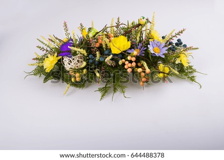 Colorful composition made of artificial flowers, fruits, butterflies, birds and ears of wheat in stylish vase on white background.