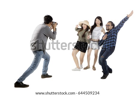 Asian man using a digital camera for taking a picture his friends while standing in the studio