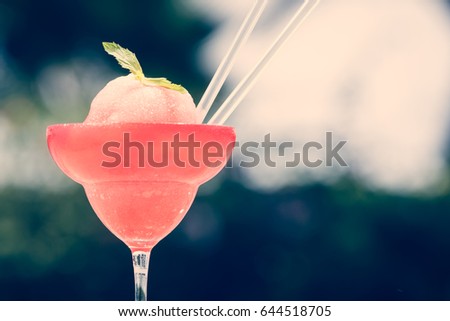 Frozen strawberry margarita cocktail at the edge of a resort pool. Concept of luxury vacation. Outdoor pool background. Horizontal, toned, overlighted image