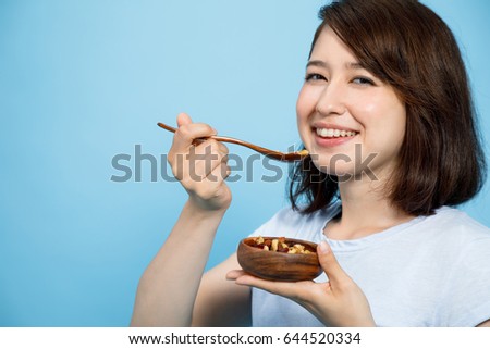 young woman eating granola on blue background. Macrobiotics concept.