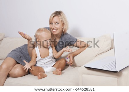 Happy family. Beautiful mother and son are sitting on the couch. Child with a computer.