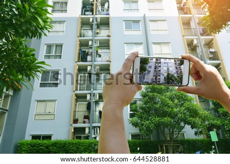 Businesswoman holding smartphone taking pictures view of condominium for rent in the green city - Real estate of concept