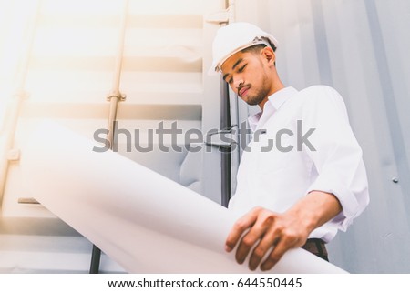 Civil engineer holding blueprint at the construction site.