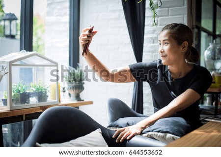 Asian business women using smart phone for take a photo in coffee shop.