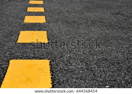 Yellow paint line on black asphalt. space transportation background - closeup