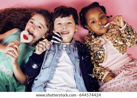lifestyle people concept: diverse nation children playing together, caucasian boy with african little girl holding candy happy smiling closeup
