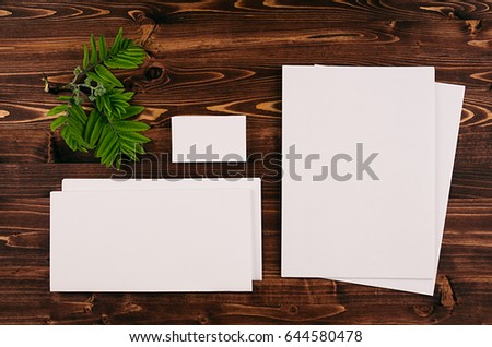 Corporate identity template, stationery with green foliage on vintage brown wooden board. Mock up for branding, graphic designers presentations and portfolios.