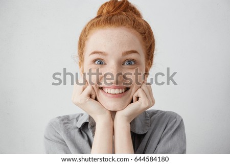 Tell me more. Close up shot of curious 20 y.o. redhead Caucasian woman pillowing face on her hands and looking at camera with anticipation and excitement while listening to story or gossips Royalty-Free Stock Photo #644584180
