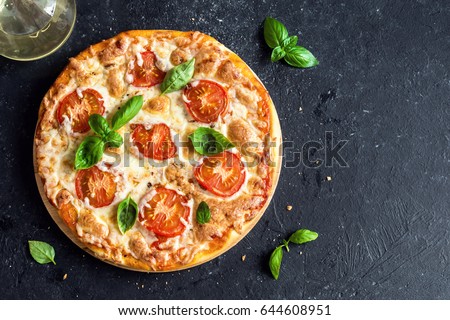 Pizza Margherita on black stone background, top view. Pizza Margarita with Tomatoes, Basil and Mozzarella Cheese close up. Royalty-Free Stock Photo #644608951