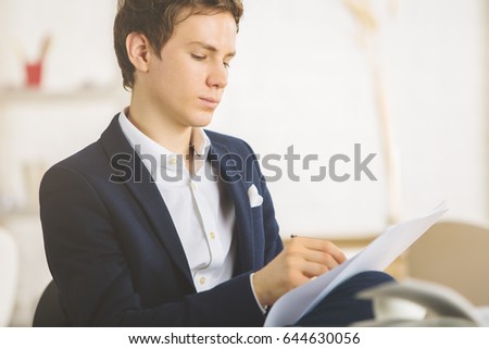 Portrait of handsome young male doing paperwork at workplace
