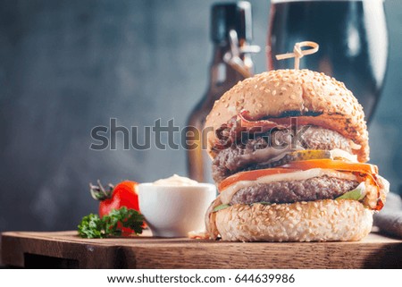 Homemade fresh hamburger and dark beer on wooden background in vintage style