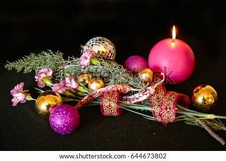 Christmas bouquet with burning candle, red roses, bush carnations, pine cones, cypress branches, pink pepper and yellow balls. New Year composition on a dark background.