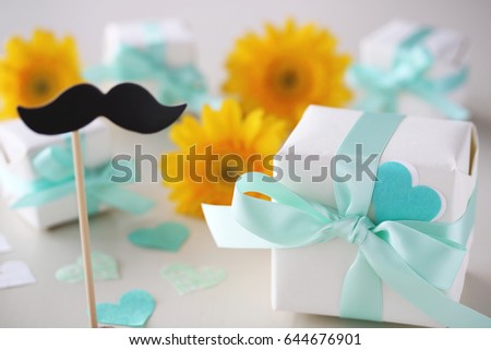 Gift boxes with pale blue bow, gerber flowers,paper mustache and paper hearts 