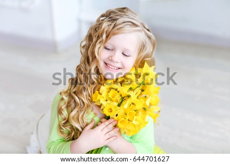 Sweet girl with blue eyes, blonde, with a bouquet of yellow daffodils