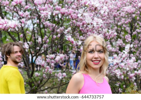 girl and guy, couple in love in spring magnolia flowers, happy smiling man and woman in garden with blossom tree outdoor on natural background