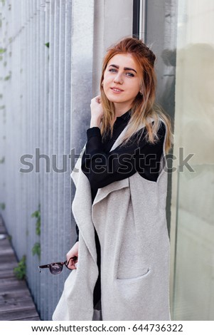 One girl pose to camera near the wall with sunlight background