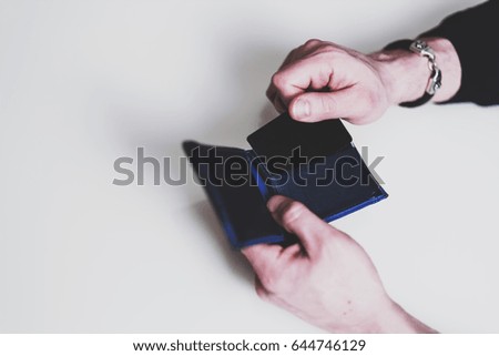 Shopper takes the black credit card out of wallet. Man's hand takes a bank card from the wallet on white background