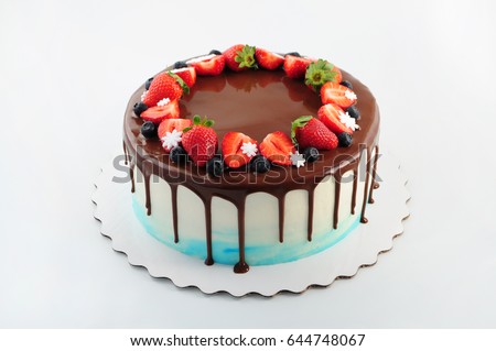 Birthday cake in chocolate with strawberries, blueberries and snowflake on white background. Picture for a menu or a confectionery catalog.