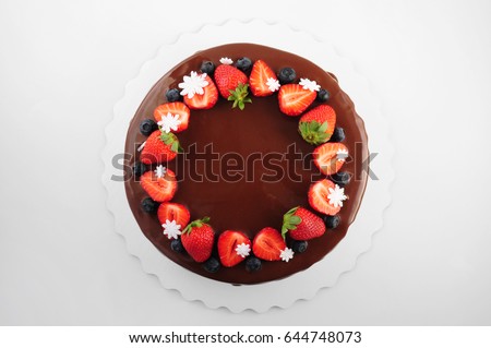 Birthday cake in chocolate with strawberries, blueberries and snowflake on white background. Top view. Picture for a menu or a confectionery catalog.