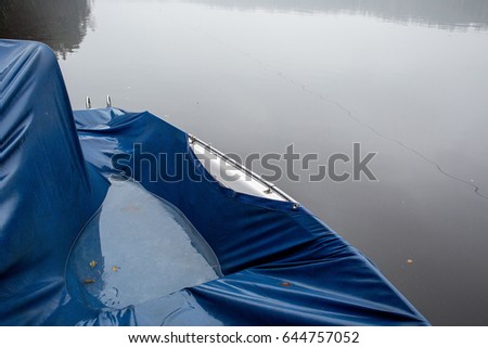 the boat under a tarpaulin at the lake