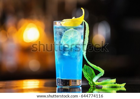 Closeup glass of blue lagoon cocktail decorated with lime at festive bar counter background. Royalty-Free Stock Photo #644774116