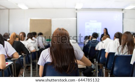 soft focus back student.blur abstract background of examination room with undergraduate students inside. student sitting on row chair doing final exam in classroom and professor front of room.
