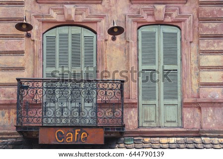 Fragment of the old city cafe with a sign on the balcony and windows with shutters
