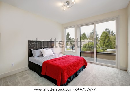 Upstairs bedroom interior with a balcony, minimalistic style: Creamy walls, grey carpet floor and bed with red blanket. Northwest, USA