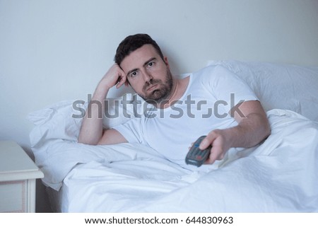 Man watching television lying in the bed
