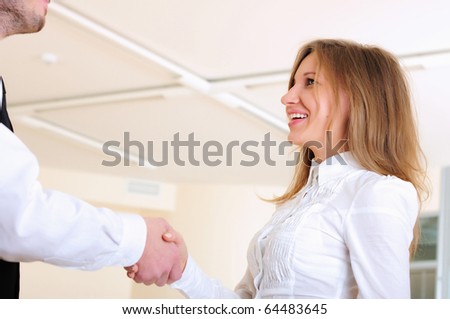 A young girl shakes hands with his colleague in the office.