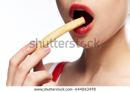 Woman eating mouth french fries, close-up of mouth and potatoes