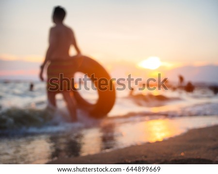 Blurred picture of a man holding life ring on the beach in sunset time for summer vacation concept background with copy space.