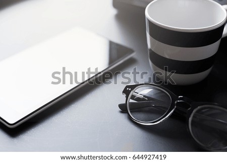 smartphone, coffee cup and eyeglasses on black background
