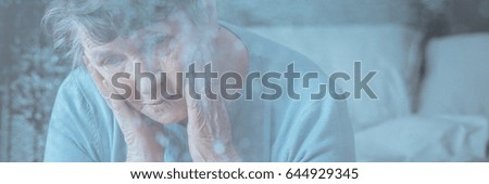 View through window of older woman having headache or migraine 