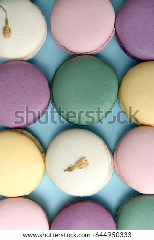 Picture of a lot of sweet colorful macaroons on blue table background.